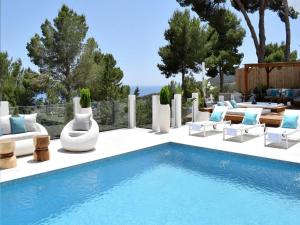 a pool with chaise lounge chairs and a swimming pool at Villa in Ibiza with Sea Views and Jacuzzi in Es Cubells
