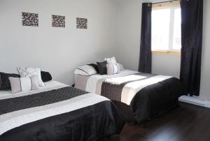 1 dormitorio con 2 camas y sábanas blancas y negras en Hébergement Italia, en La Tuque