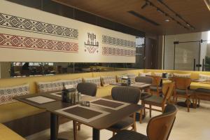 a restaurant with tables and chairs and a wall at G Hotel Amman in Amman