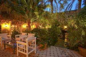 a patio with white chairs and trees and lights at DAR ELHADIR in Tozeur