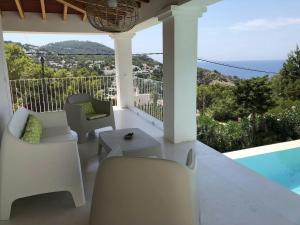 サン・ホセにあるVilla in Cala Vadella with Infinity Pool & Beachのバルコニー(椅子、テーブル、プール付)