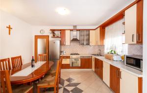 kuchnia z drewnianymi szafkami, stołem i blatem w obiekcie Cozy Home In Posedarje With Wifi w mieście Posedarje
