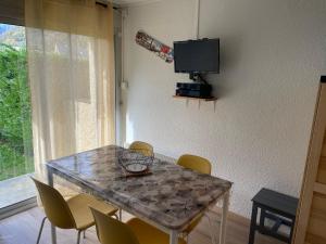a dining room table with chairs and a television at Appt hyper centre Saint-Lary-Soulan village avec jardin in Saint-Lary-Soulan