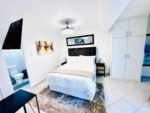 a white bedroom with a bed and a bathroom at Hotel Vibes Cape Town Plattekloof in Cape Town