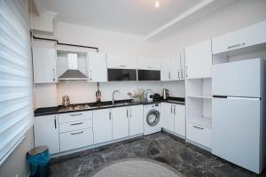 a white kitchen with a sink and a dishwasher at One Suit in Kartepe