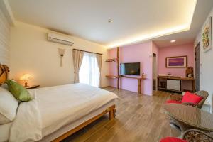 a bedroom with a bed and chairs and a television at 緣木屋庭園民宿 in Dongshan