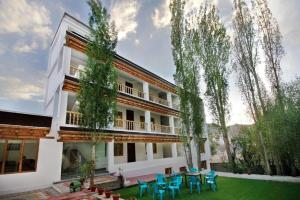 an exterior view of a building with a yard with blue chairs at Hotel Ladakh Marvel Leh in Leh +16 photos