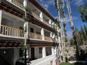 a white building with a balcony and some palm trees at Hotel Ladakh Marvel Leh in Leh