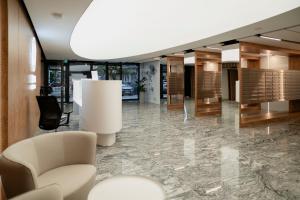 a lobby with a white chair and a table at Global Apartments Katowice in Katowice