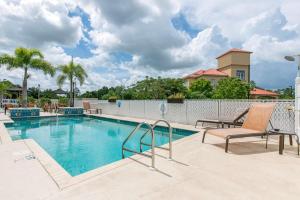 a swimming pool with two lounge chairs next to a building at Sleep Inn & Suites Port Charlotte-Punta Gorda in Port Charlotte