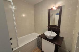 a white bathroom with a sink and a bath tub at Appartement 4 personnes avec accès piscine in La Féclaz