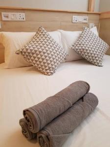 Heritage Loft on Beach Street near UNESCO Zone & Street Art 3 في جورج تاون: منشفة مطوية على سرير مع الوسائد