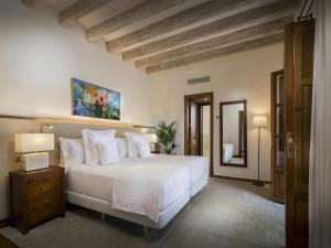 een slaapkamer met een groot wit bed en een spiegel bij Elegant villa with communal space in Banyalbufar