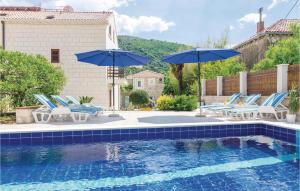 a pool with chairs and umbrellas next to a house at Holiday Home Obuljeno Donje Iii in Mokošica