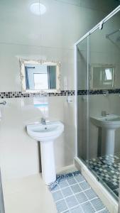 een witte badkamer met een wastafel en een douche bij Golden View Boutique Guesthouse in Windhoek