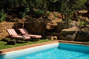 two chairs and a table next to a swimming pool at Bartinney Private Cellar Banhoek in Stellenbosch