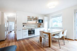a kitchen with white cabinets and a wooden table and chairs at Grenzberg, Bad Gastein - Rooftop in Bad Gastein