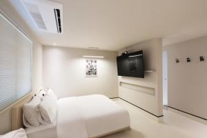 a white bedroom with a bed and a flat screen tv at Hotel RUGO in Jeonju