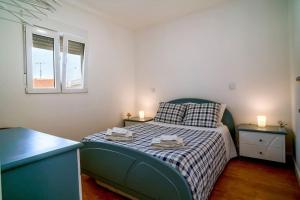 a small bedroom with a bed and two windows at Casa da fonte in Vila Nova de Gaia
