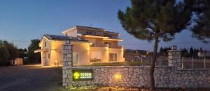 a large white house with a tree in front of it at TEGEA LUXURY SUITES Aphrodite in Tripoli