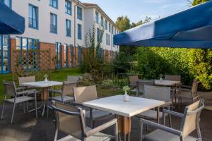 a row of tables and chairs with blue umbrellas at Sunday Hotel and Spa Wismar in Wismar