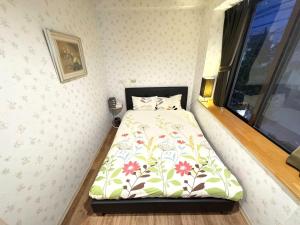 a small bedroom with a bed with a floral bedspread at 鶴の宿 那覇-国際通りまで950mの便利な立地-1棟貸切 in Naha
