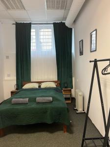 a bedroom with a bed with green sheets and a window at TomTom Hostel in Krakow