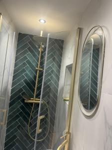 a bathroom with a shower with blue tiles and a mirror at Studio Bagneux Bourg la Reine in Bagneux
