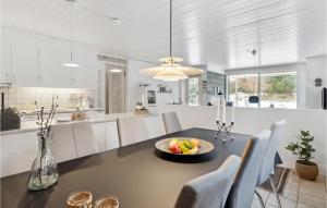 a kitchen and dining room with a table with a bowl of fruit at Holiday Home Sandtoftevej Blåvand Ix in Blåvand