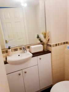 a bathroom with a white sink and a mirror at Chelmsford Comfort Retreat Spacious 4 Bedroom Sleeps 7 Free Parking in Widford +40 photos