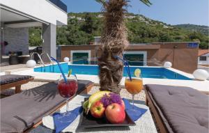 ein Tablett mit Obst und Getränken auf einem Tisch neben dem Pool in der Unterkunft Four-Bedroom Apartment In Klek in Klek