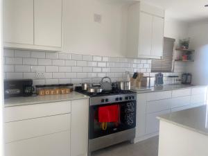 Una cocina con gabinetes blancos y un horno de estufa. en The View, en Saldanha