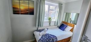 a small bedroom with a bed and a window at Chelmsford Comfort Retreat Spacious 4 Bedroom Sleeps 7 Free Parking in Widford