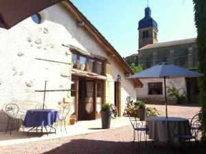 two tables and an umbrella in front of a building at La Grange in Coutouvre