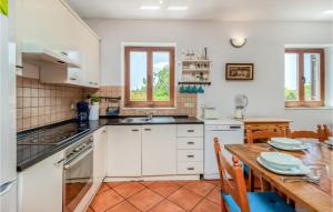 kuchnia z białymi szafkami i drewnianym stołem w obiekcie 4 Bedroom Gorgeous Home In Dobrinj w mieście Dobrinj