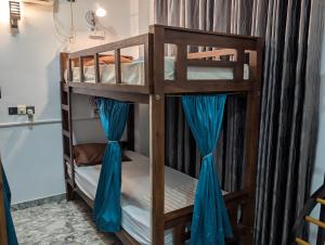 two bunk beds in a room with blue curtains at Costels Mirissa in Mirissa