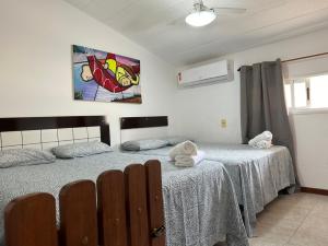 a bedroom with two beds and a painting on the wall at Duplex Arembepe, beira mar, piscina i wifi in Camaçari +67 photos