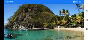a beach with a mountain and a boat in the water at Une petite halte à Terre-de-Haut in Terre-de-Haut +3 photos