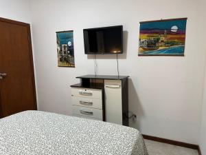 a bedroom with a bed and a flat screen tv at Duplex Arembepe, beira mar, piscina i wifi in Camaçari