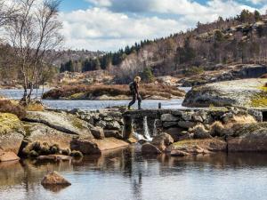 Un uomo che attraversa un ponte sul fiume di 7 person holiday home in lyngdal a Lyngdal