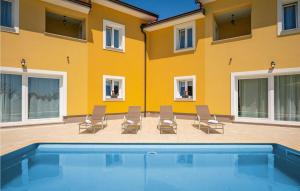 a yellow building with chairs and a swimming pool at Villa Terra in Mošćenička Draga