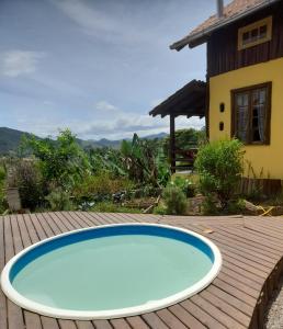 a swimming pool on a wooden deck next to a house at Chalé Sol da Montanha em Termas do Gravatal - SC in Gravatal