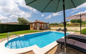 a swimming pool with an umbrella and a house at Villa Morena in Buje