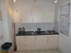 een keuken met witte kasten en een wastafel bij Airport Apartment in Düsseldorf