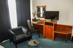 a living room with a television and a chair at Miros Restaurant Steakhaus Hotel in Langenfeld