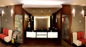 ein Empfangsbereich mit roten Stühlen und einem Empfangstresen in der Unterkunft Roomz Hotel in Seria
