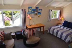 a bedroom with a bed and a desk and chairs at Le Loft in Akaroa