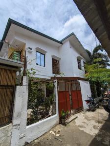 a white house with red doors and a fence at Francis Dale Lodge L3 in El Nido