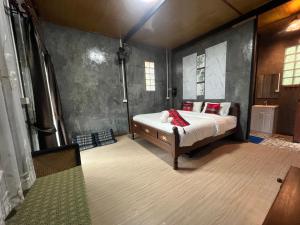 a bedroom with a bed with red pillows on it at บ้านต้นไม้แม่กำปอง Baan TONMAI MAEKAMPONG in Chiang Mai