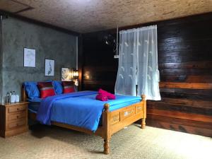 a bedroom with a bed with blue sheets and red pillows at บ้านต้นไม้แม่กำปอง Baan TONMAI MAEKAMPONG in Chiang Mai